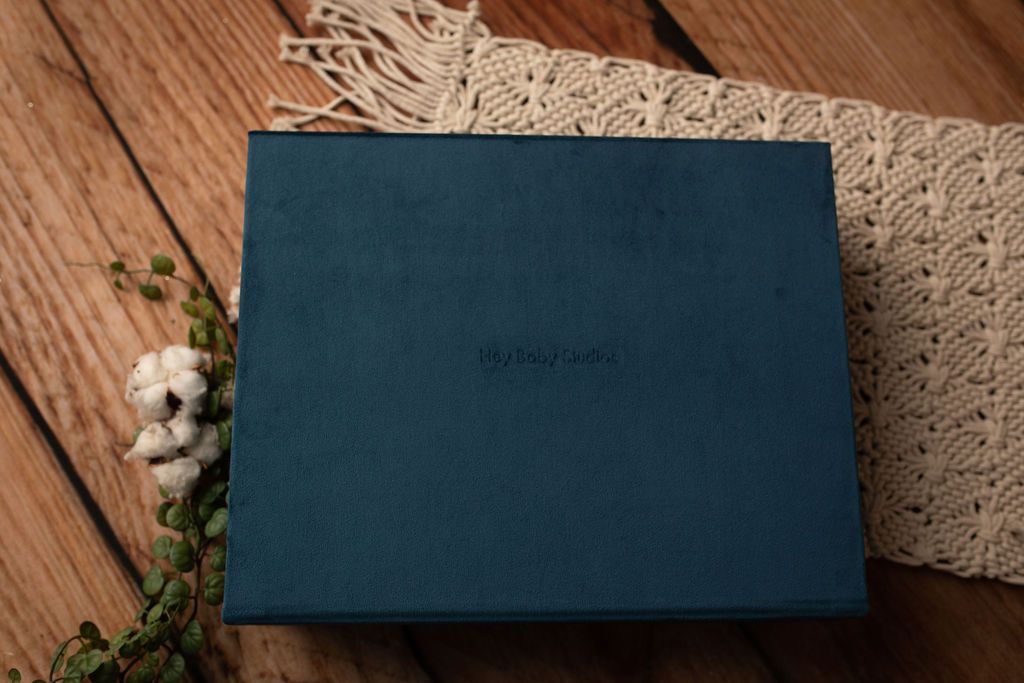 Blue box on a wooden surface, with a macrame runner and cotton sprig.