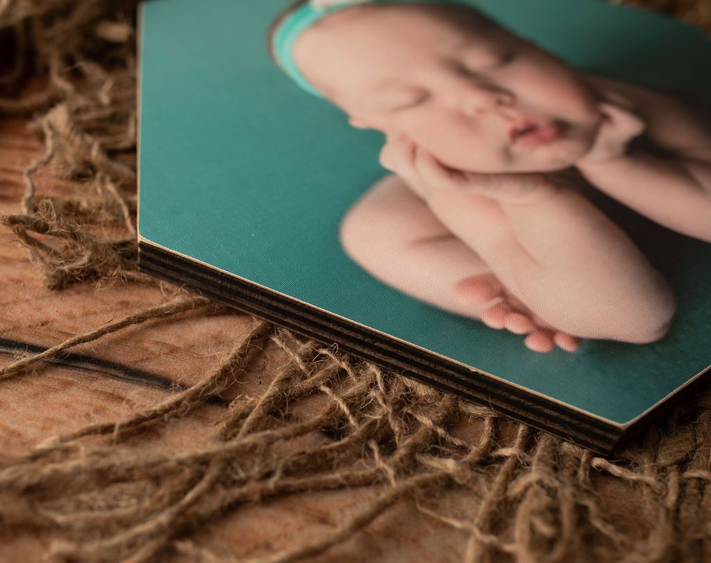 Close-up of baby photo on wooden backing with layers, resting on brown twine.
