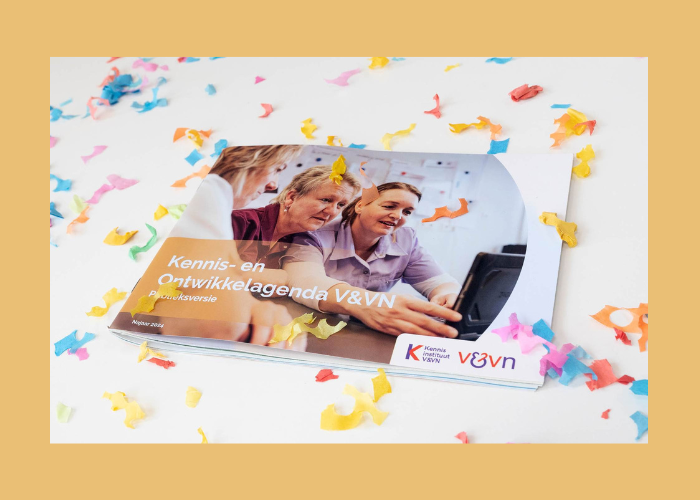Kleurrijke promotiebrochure met twee lachende mensen op een bank, confetti en een laptop op een witte achtergrond.