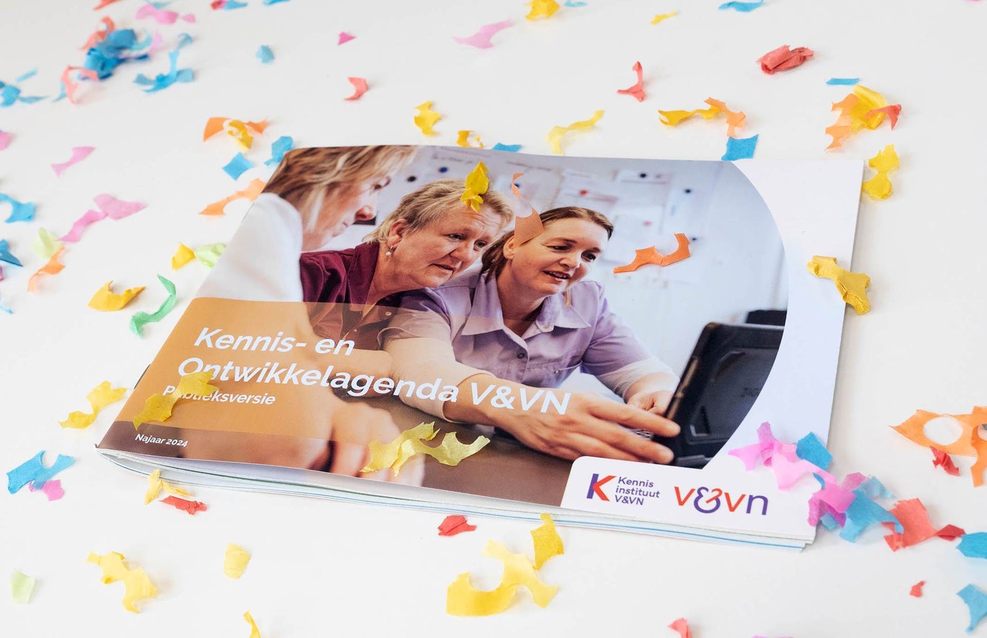 Drie lachende mensen in een auto, met kleurrijke papieren confetti en een VSVN-logo op een witte achtergrond.
