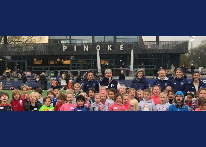 Een groep kinderen en volwassenen poseert voor een gebouw met een 