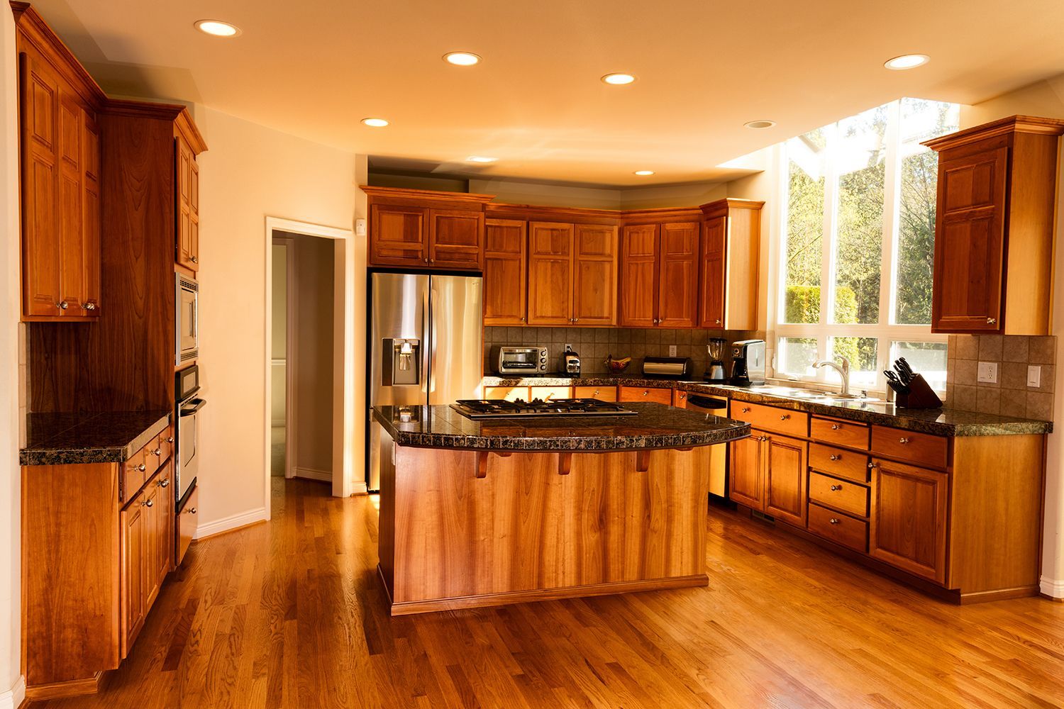 Wooden kitchen with an island, cabinets, appliances, and large windows. Wooden kitchen with an island, cabinets, appliances, and large windows.