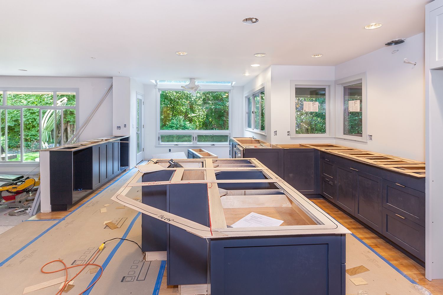 Kitchen under construction with dark blue cabinets and a central island, windows, and wood countertops. Kitchen under construction with dark blue cabinets and a central island, windows, and wood countertops.