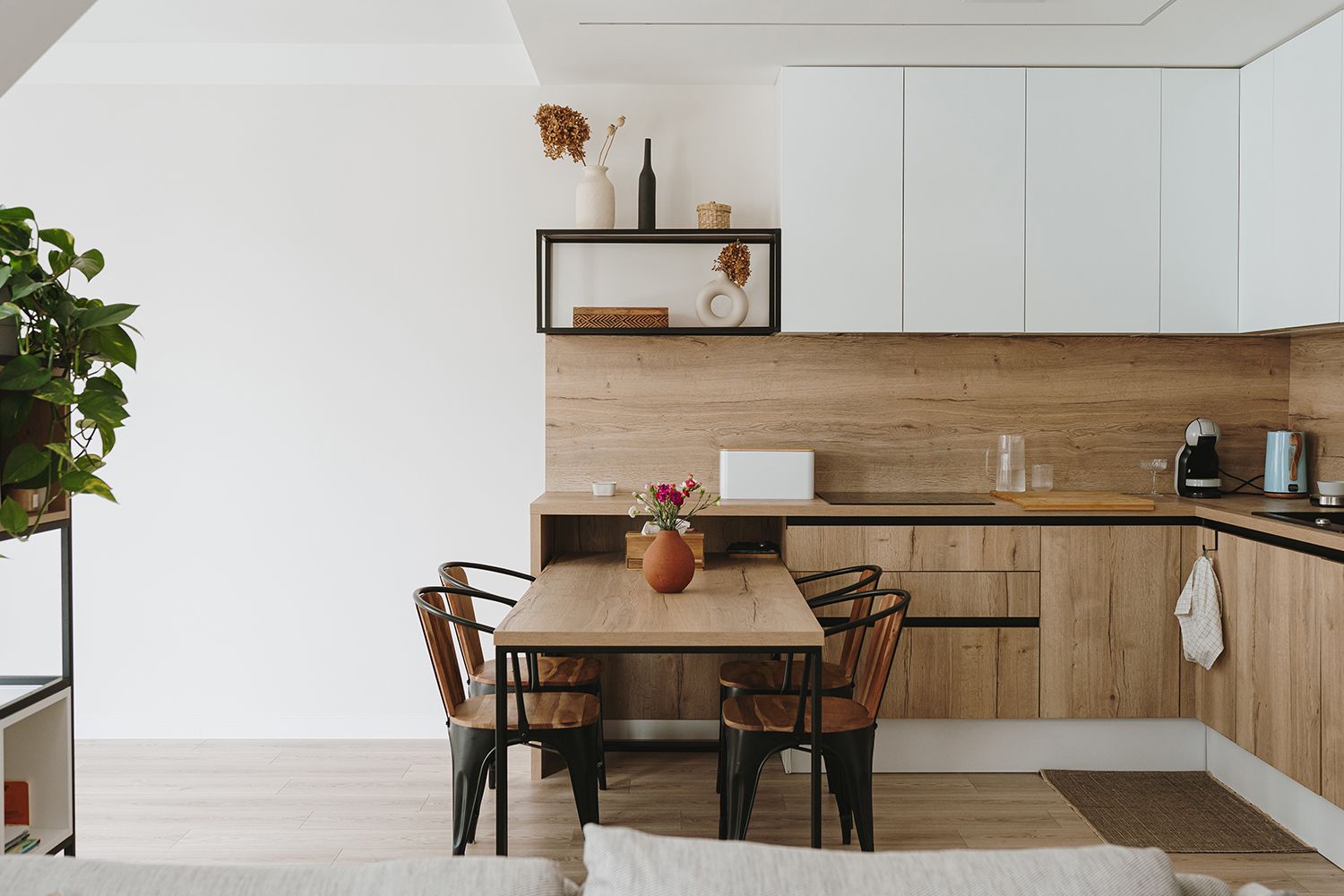 Modern kitchen with wooden cabinets, dining table, and built-in shelving.