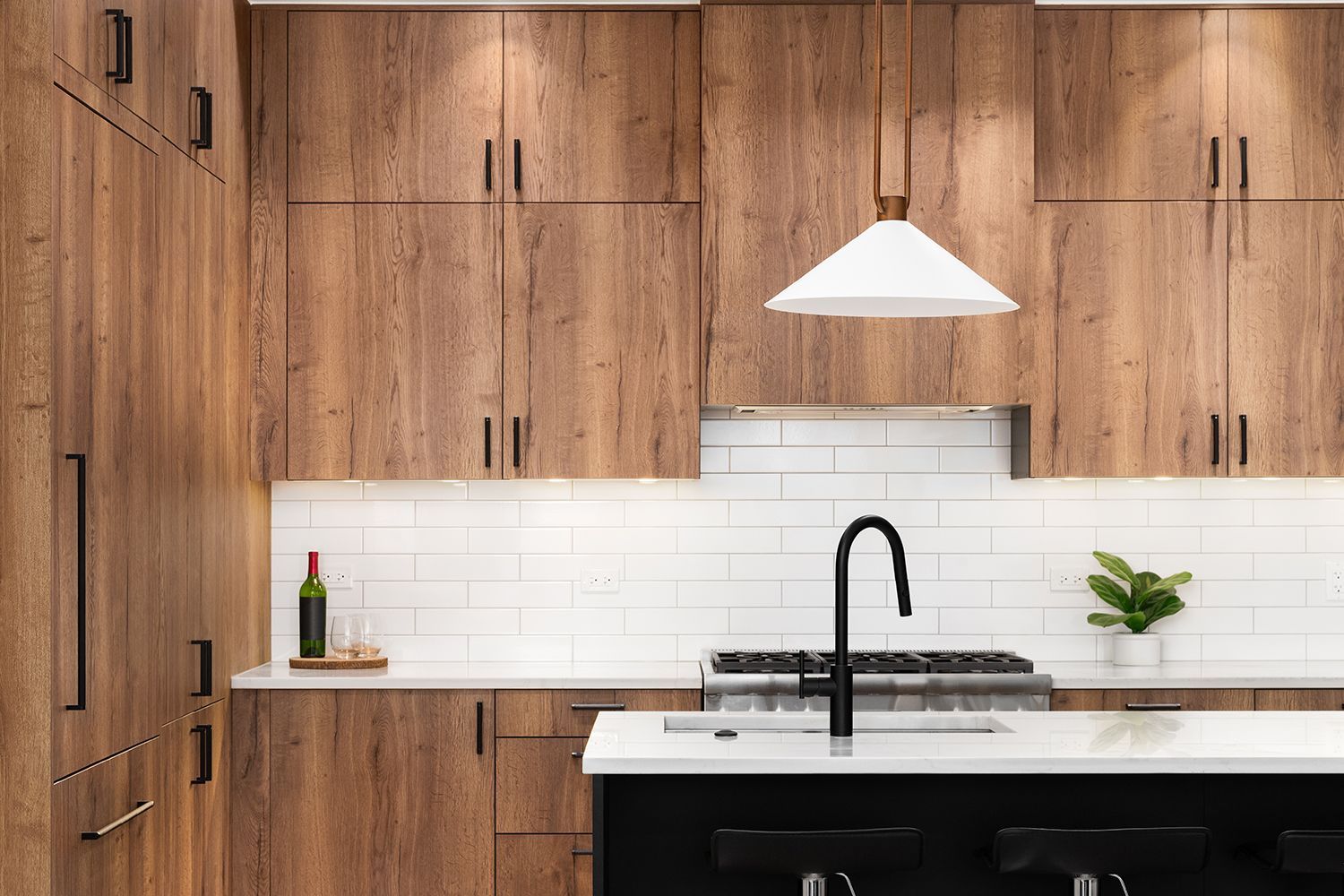 Kitchen with wood cabinets, white backsplash, black faucet, and pendant light. Kitchen with wood cabinets, white backsplash, black faucet, and pendant light.