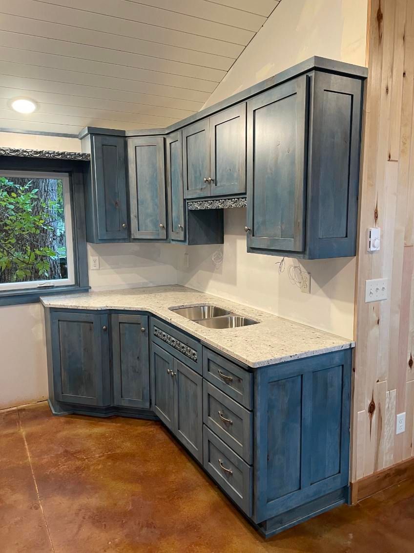 Blue kitchen cabinets with white countertops and a stainless steel sink in a corner. Blue kitchen cabinets with white countertops and a stainless steel sink in a corner.