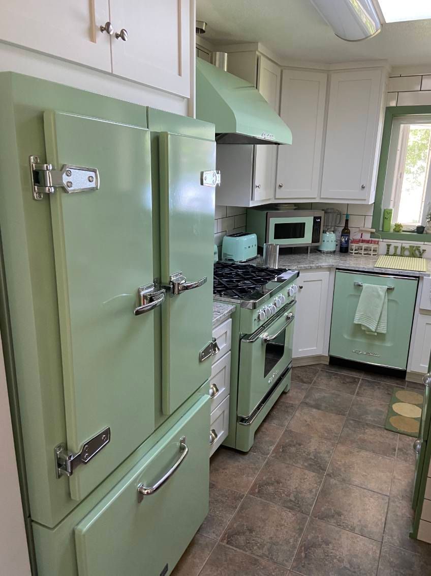 Green vintage kitchen with refrigerator, stove, and range hood. White cabinets and a brown tiled floor. Green vintage kitchen with refrigerator, stove, and range hood. White cabinets and a brown tiled floor.
