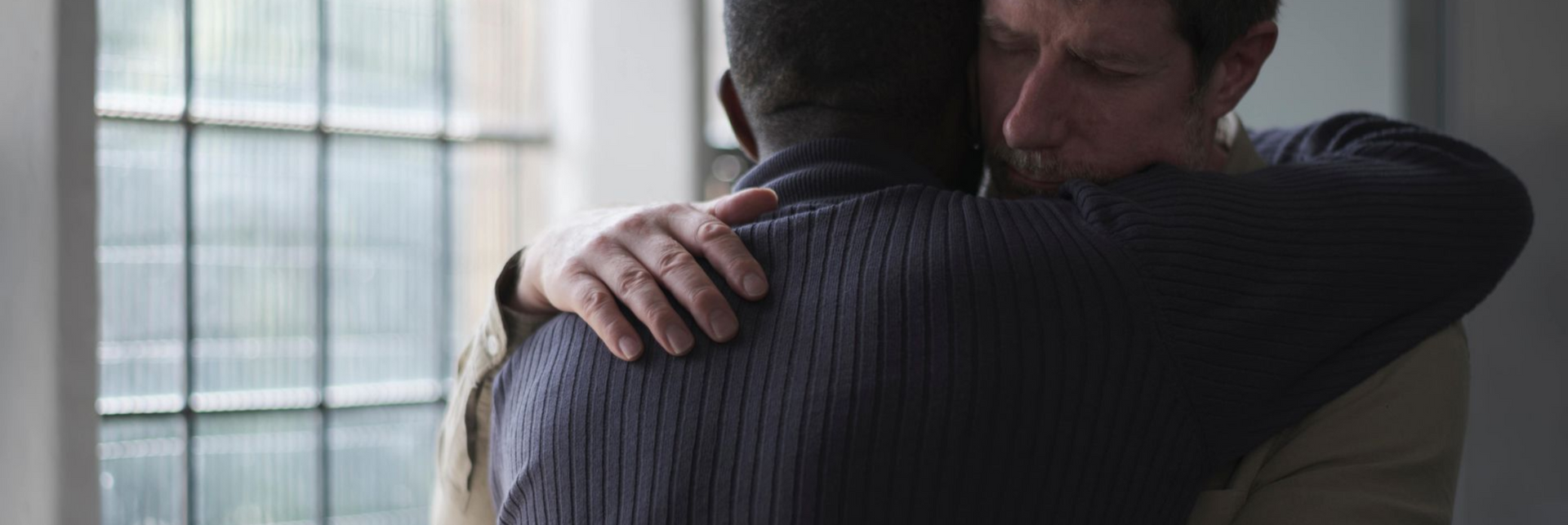 two men hugging in grief