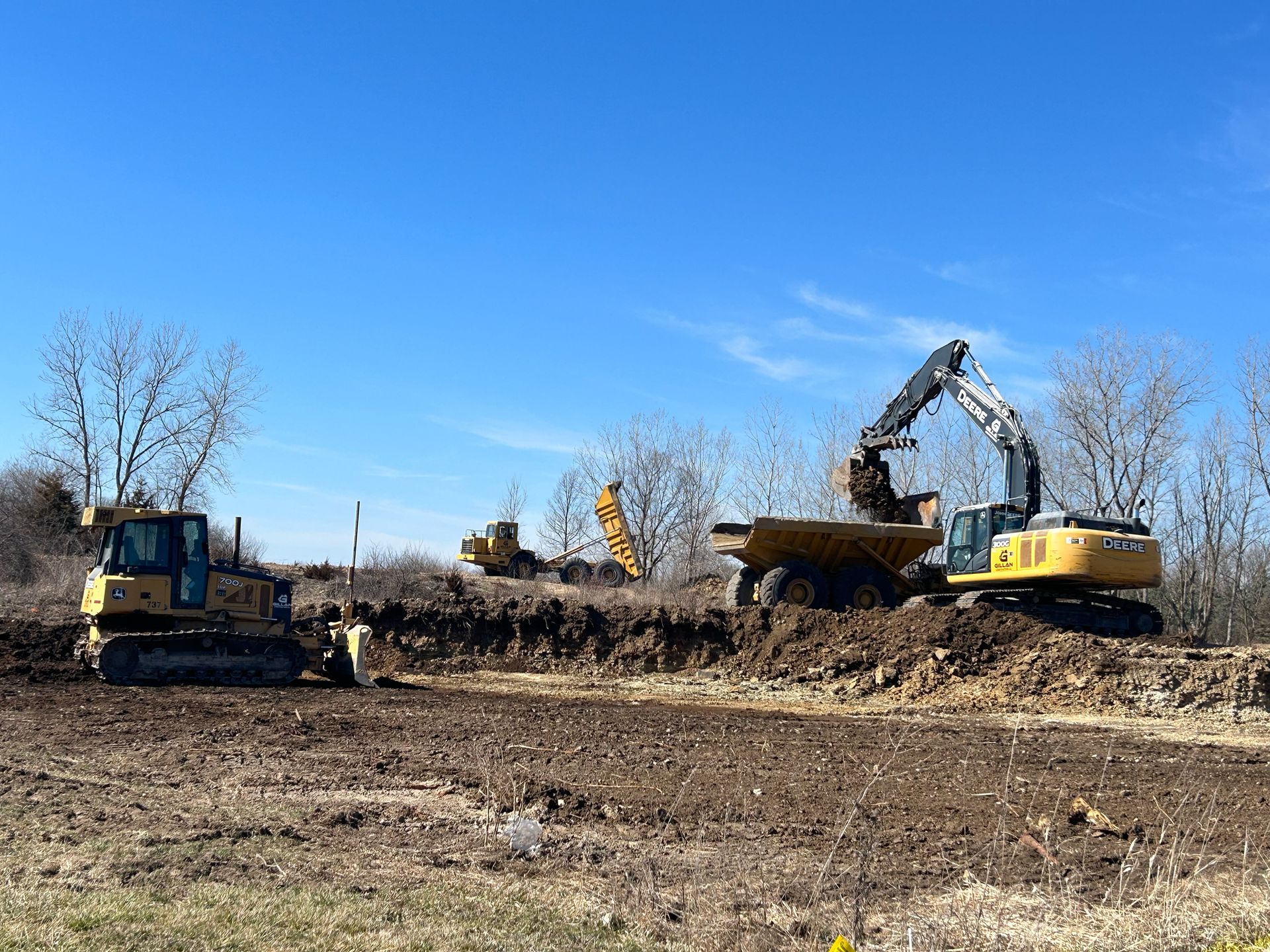 Construction site: Excavators loading a dump truck with dirt under a blue sky.