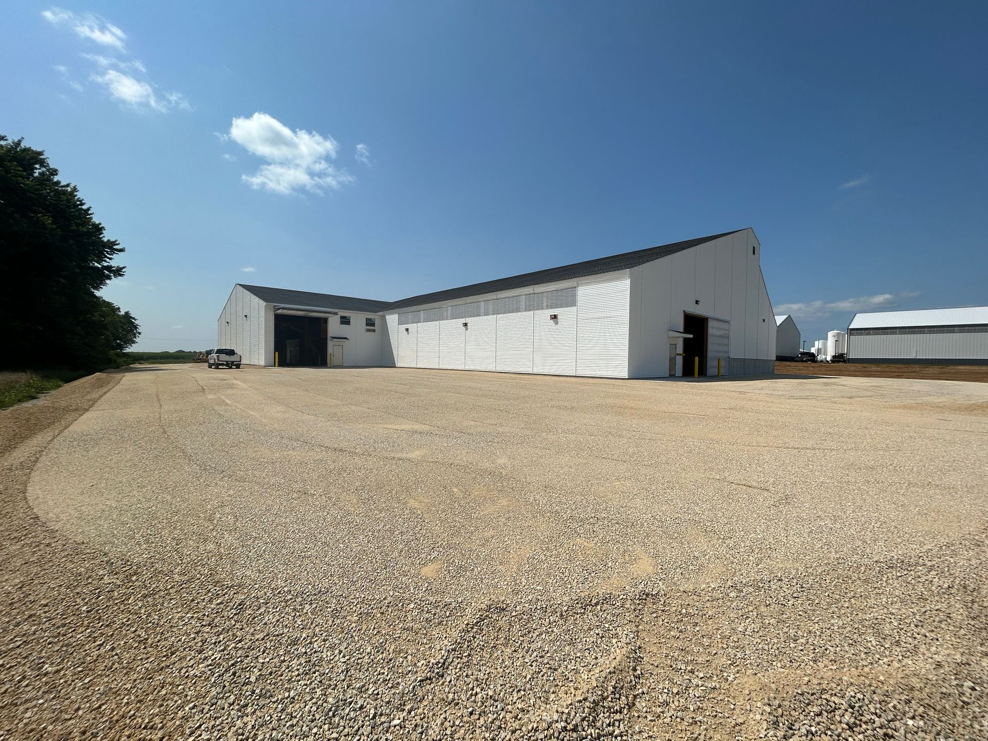 White building with a gravel driveway under a blue sky.
