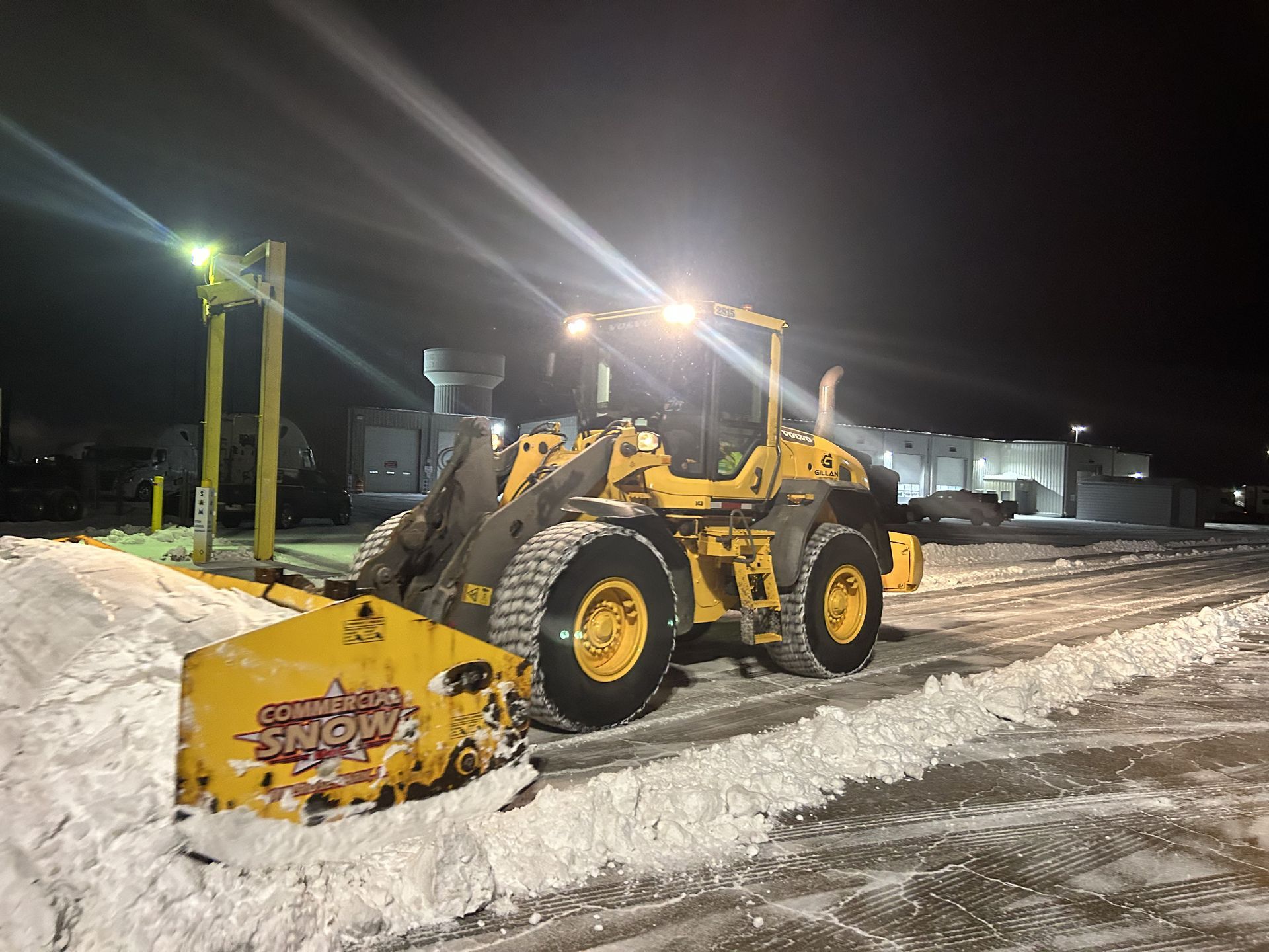 Yellow snowplow clearing snow at night.