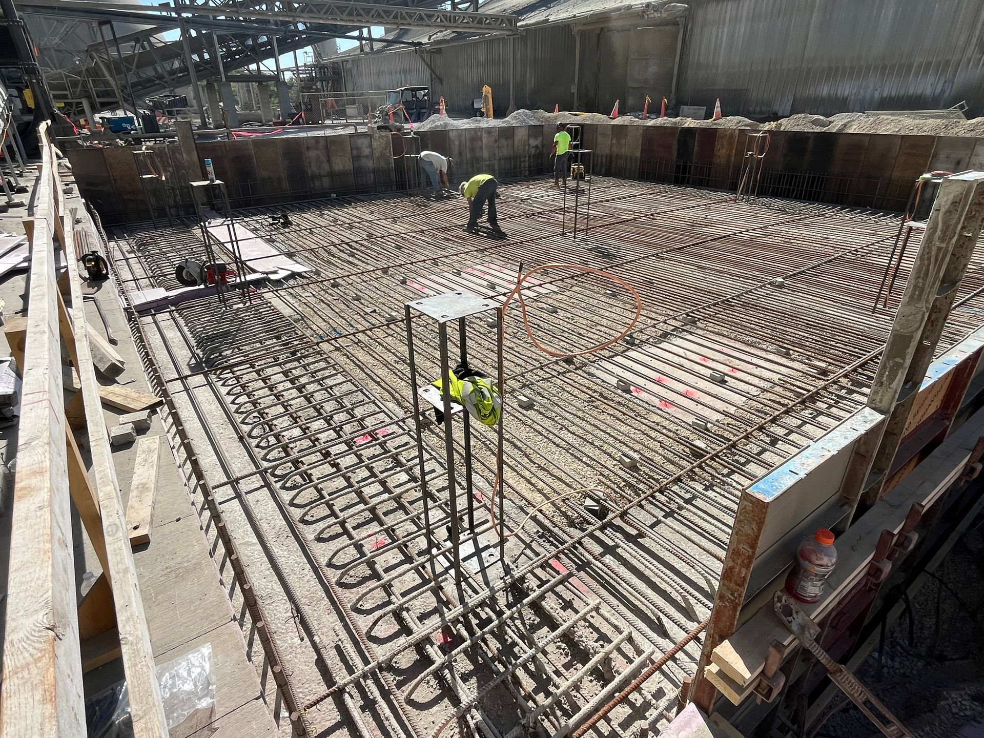 Construction site with workers, rebar, and concrete forms.