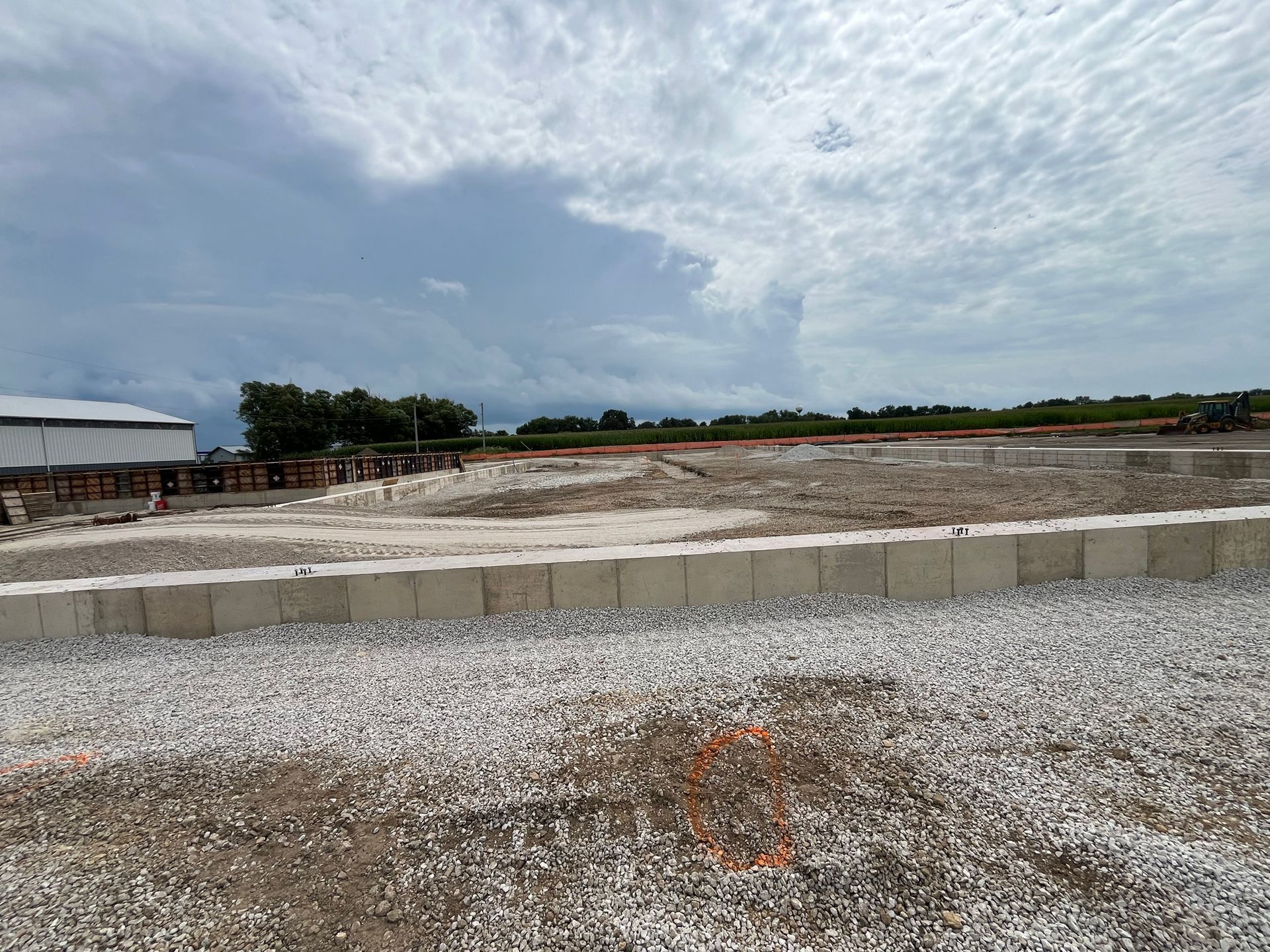 Construction site with gravel, concrete blocks, and cloudy sky.