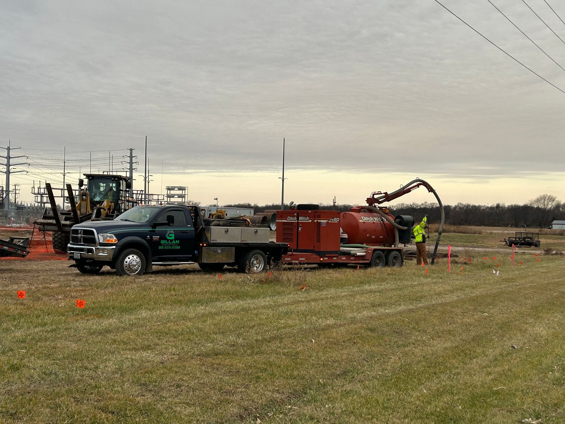 Dark green truck with trailer pumping something in a field. Cloudy sky.
