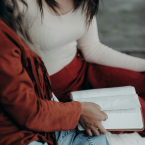 Two people sitting together, one holding an open book on their lap.