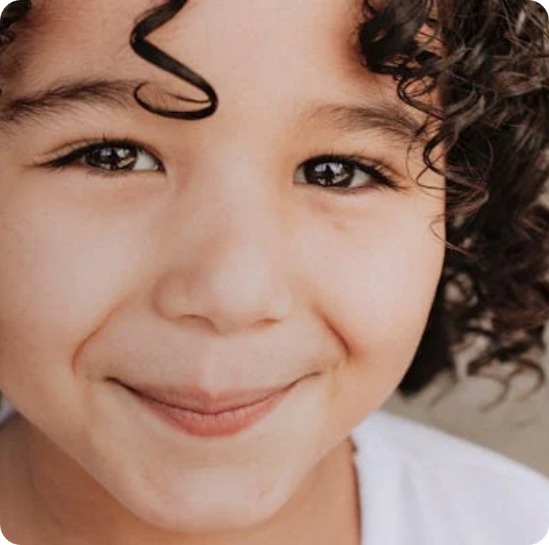 Close-up of a smiling child with curly hair and dark eyes