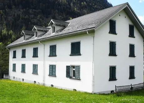 Ein weißes Gebäude mit einem grauen Dach und grünen Fensterläden