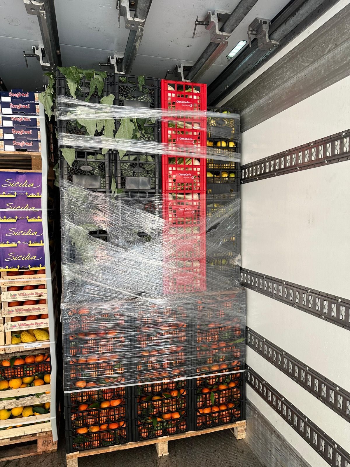 Pallet di bevande in bottiglia avvolti in pellicola termoretraibile caricati all'interno di un rimorchio refrigerato.