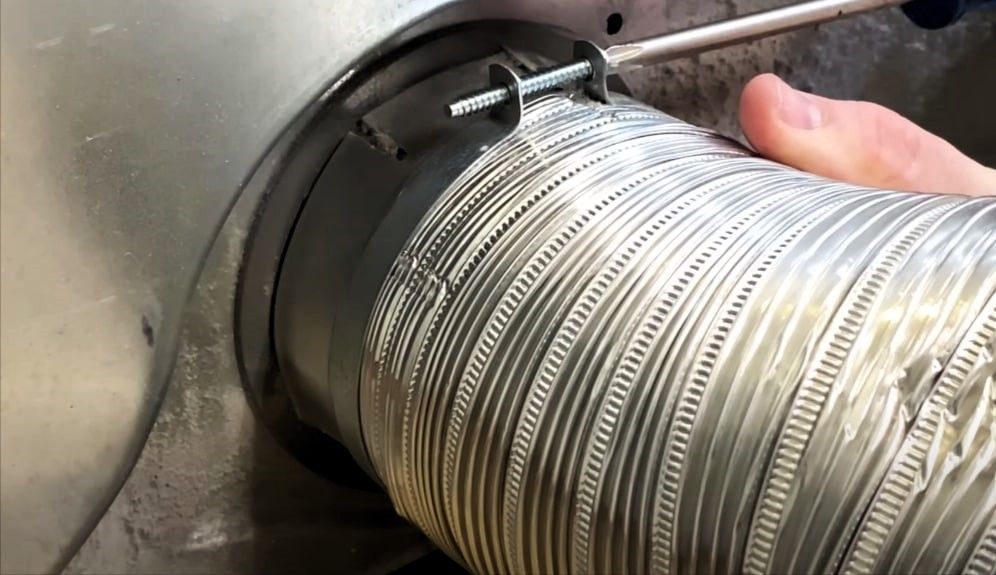 A man reassembling the flexible hose on a dryer.
