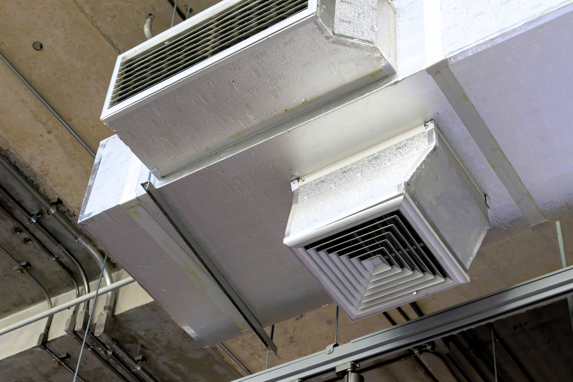 Close-up of ceiling HVAC units with metal ducts and vents