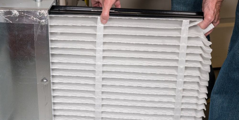 HVAC tech putting new air filter into furnace