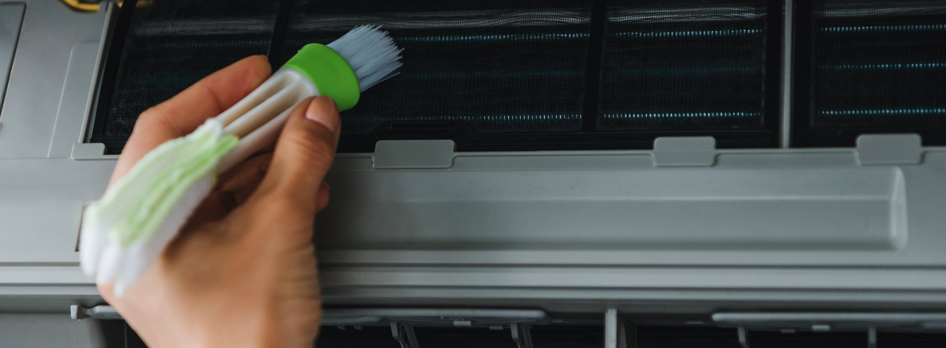 man with a brush cleaning a dirty air conditioner