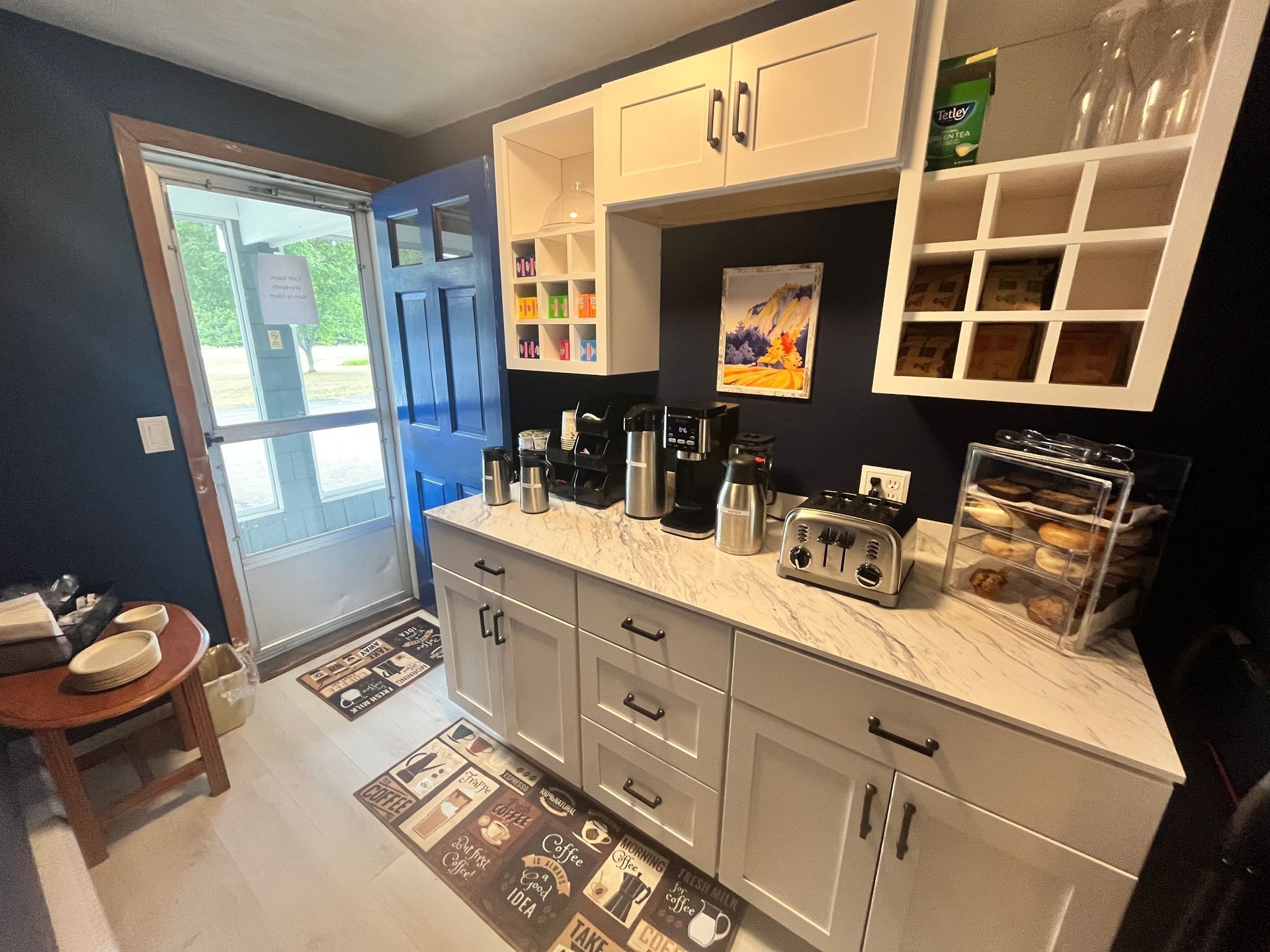 Kitchenette with white cabinets, countertop, and appliances. Blue door and wall.