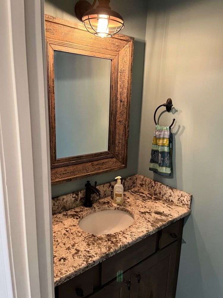A bathroom with a sink , mirror and towel rack.