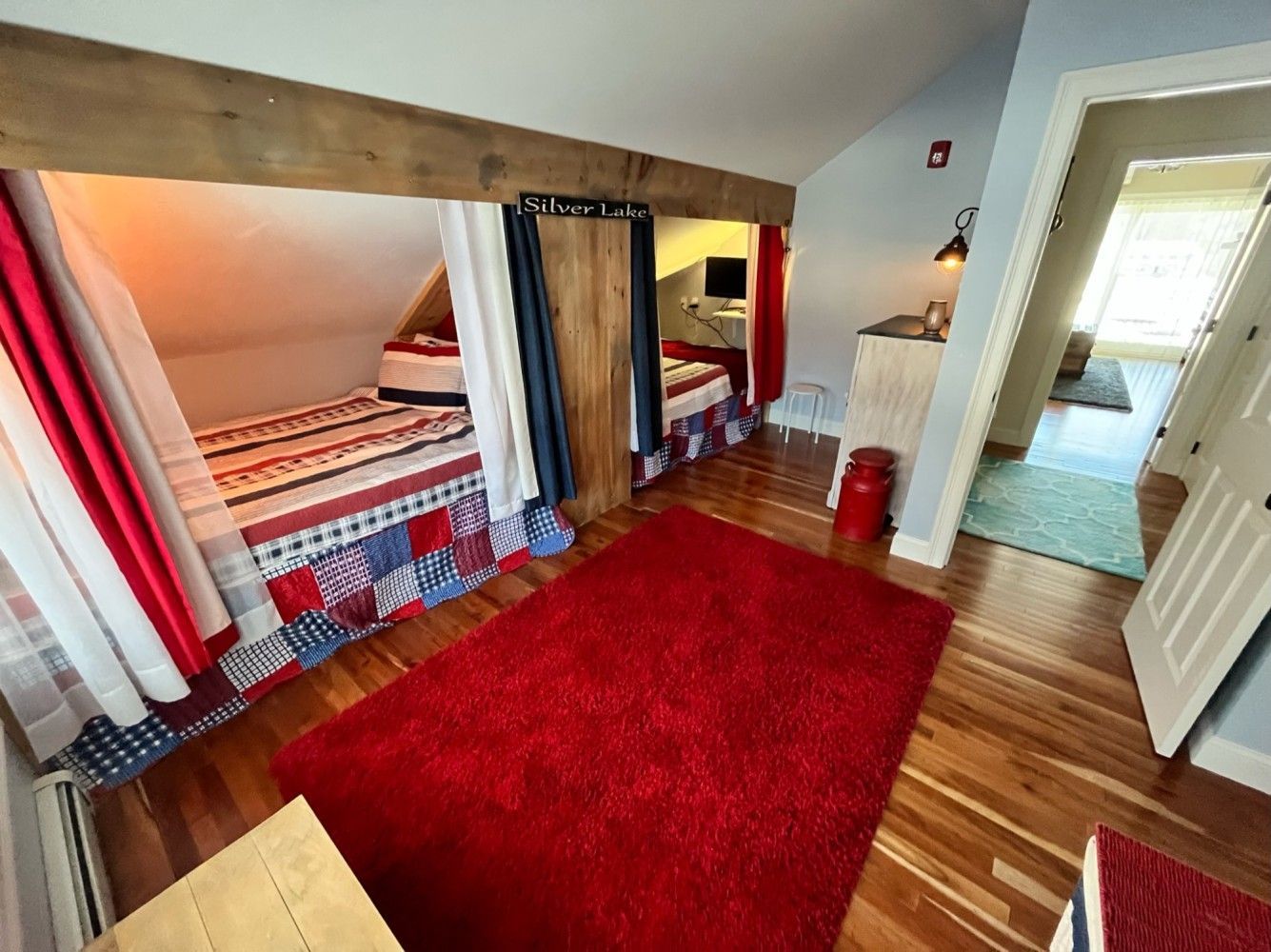 A bedroom with two beds and a red rug.