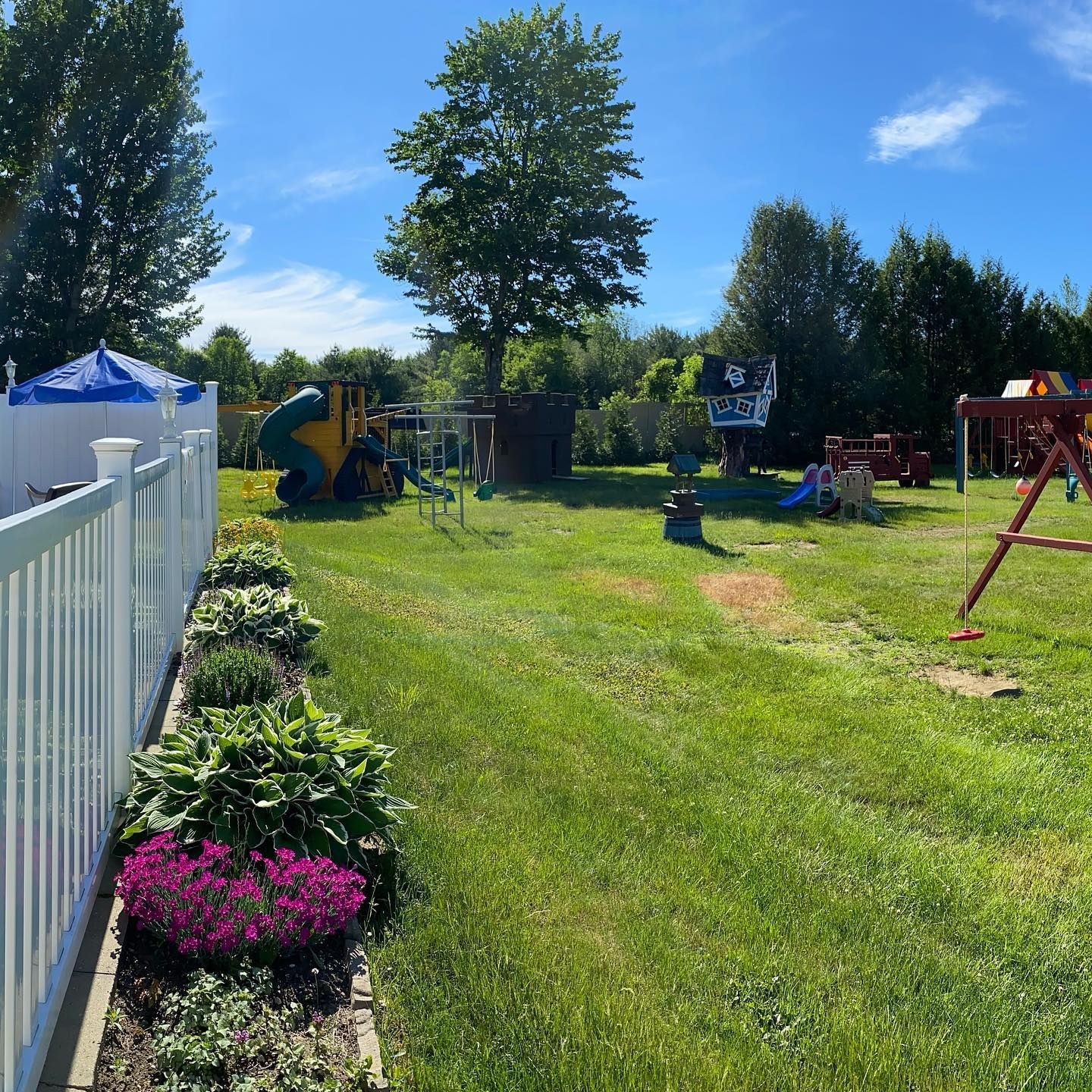 A backyard with a playground and a white fence