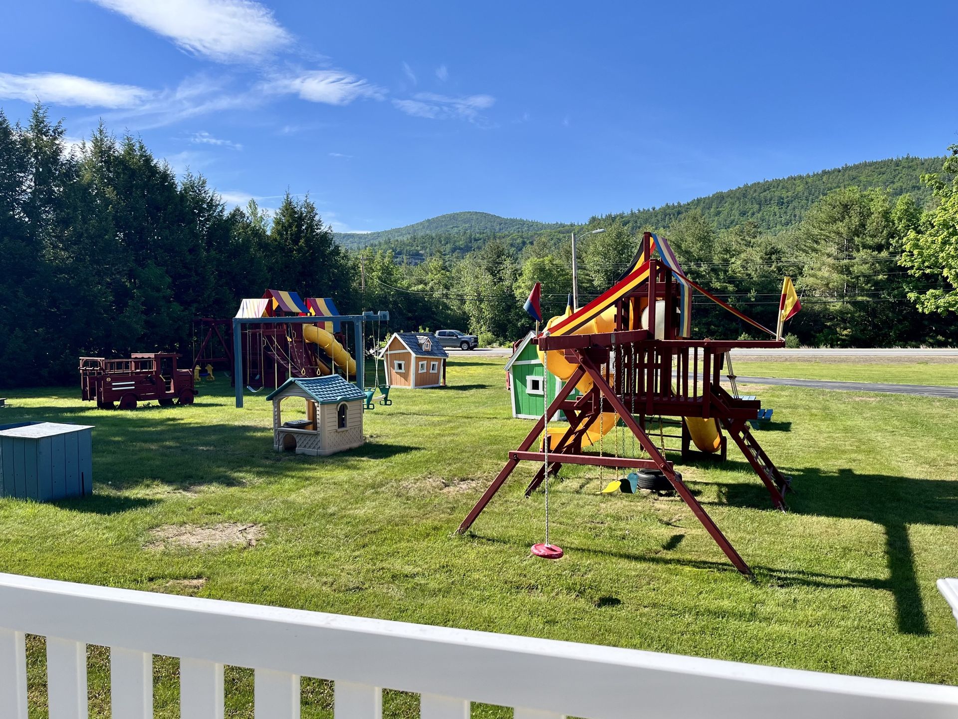 A playground with a white fence and mountains in the background.