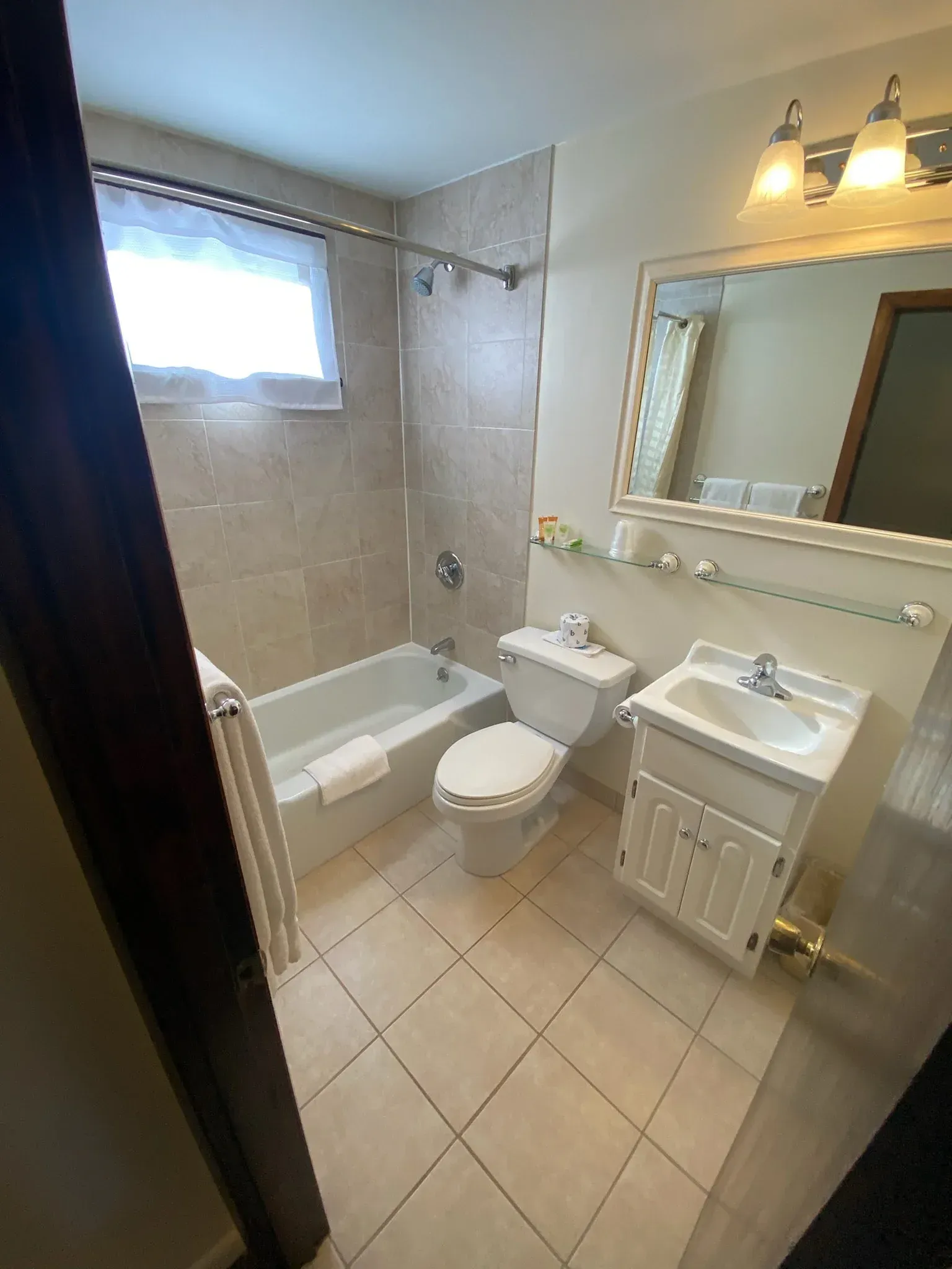 A bathroom with a toilet , sink , bathtub and mirror.