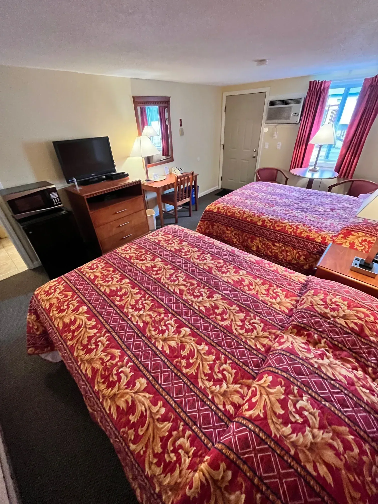 A hotel room with two beds , a desk , a television and a microwave.