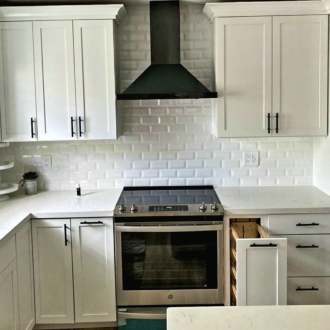 A kitchen with white cabinets and a stove top oven.