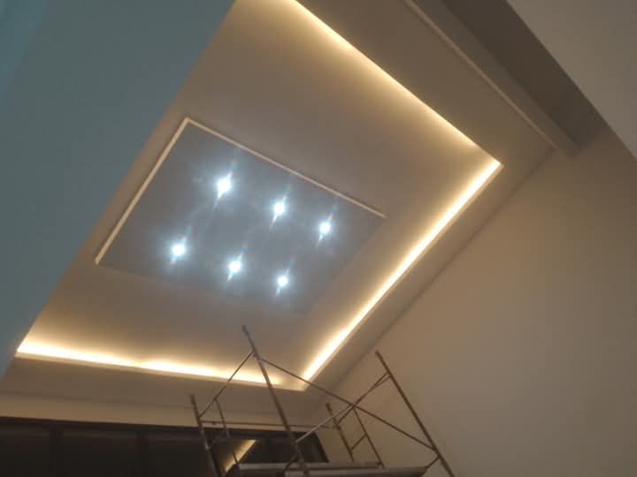 Techo con luces LED cálidas empotradas y un pequeño panel de luz central sobre el andamio.