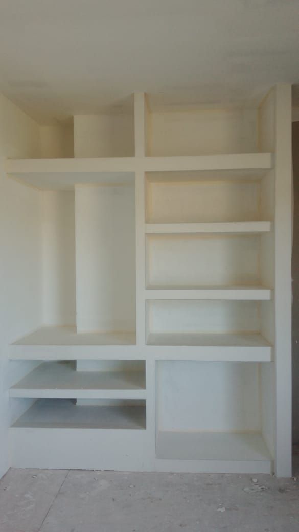 Estantería empotrada blanca en la pared, con múltiples estantes abiertos y compartimentos en una habitación.