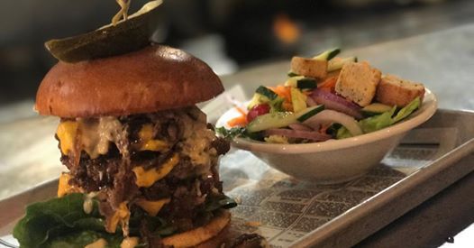 A hamburger and a salad are on a tray on a table.