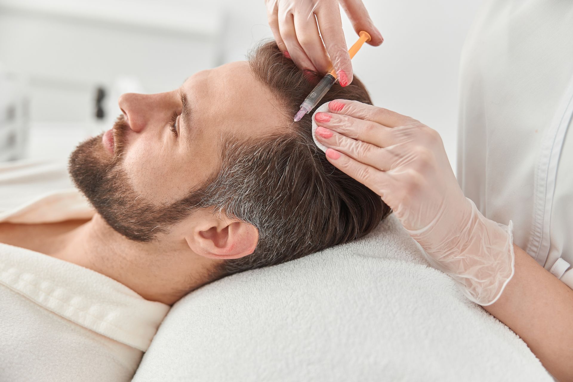 Man getting a scalp treatment with a comb in a bright spa room