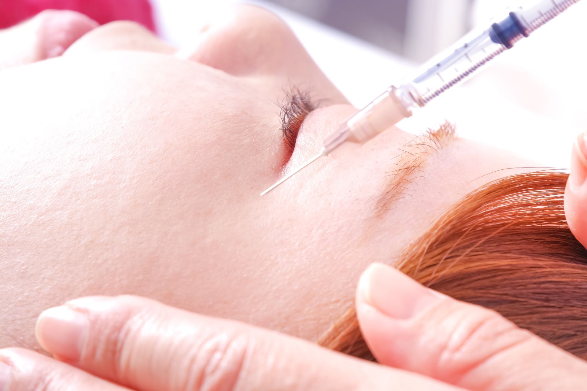 Syringe administering an injection into a person’s face near the cheek and nose
