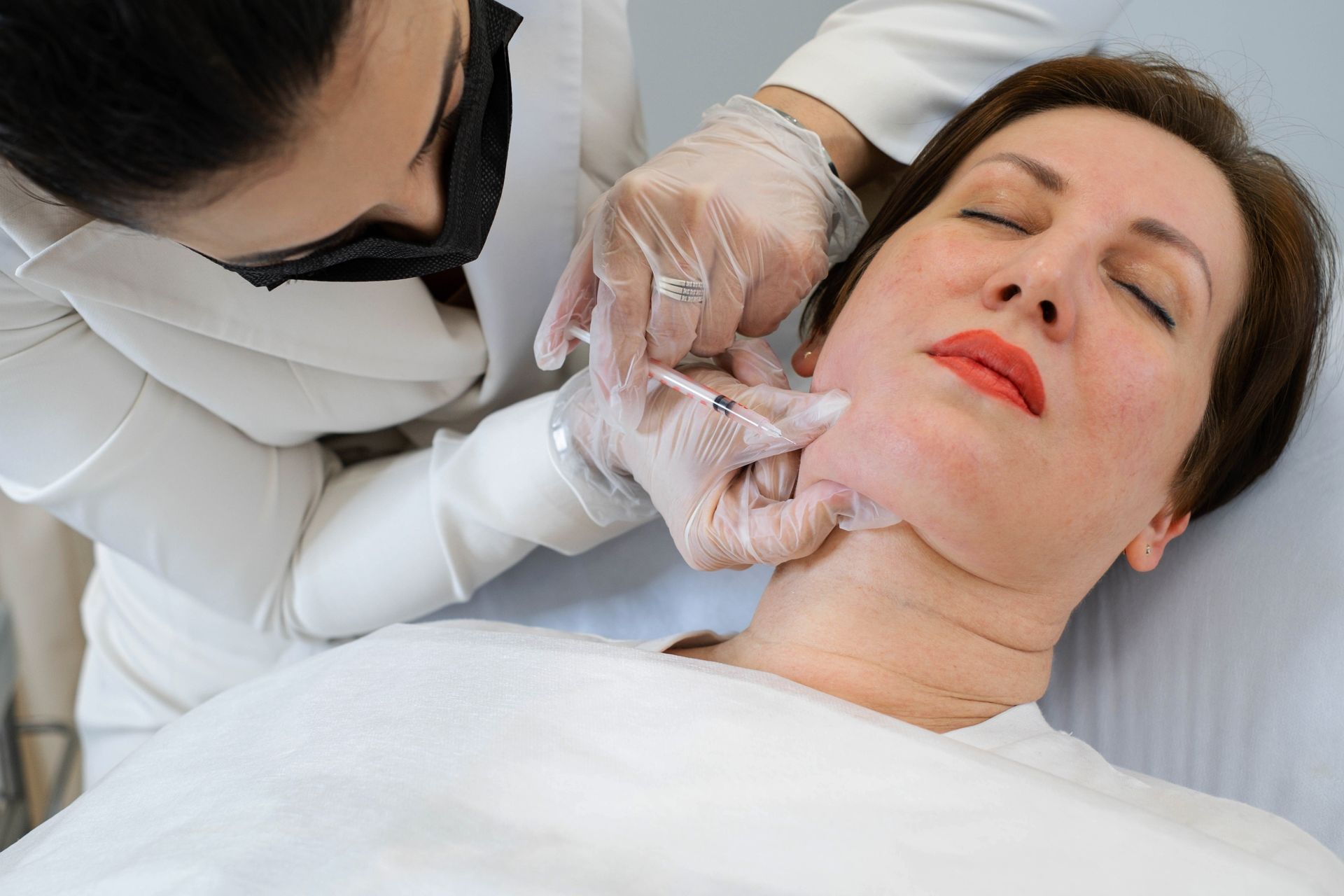 Medical practitioner adjusting a woman’s chin in a clinical setting