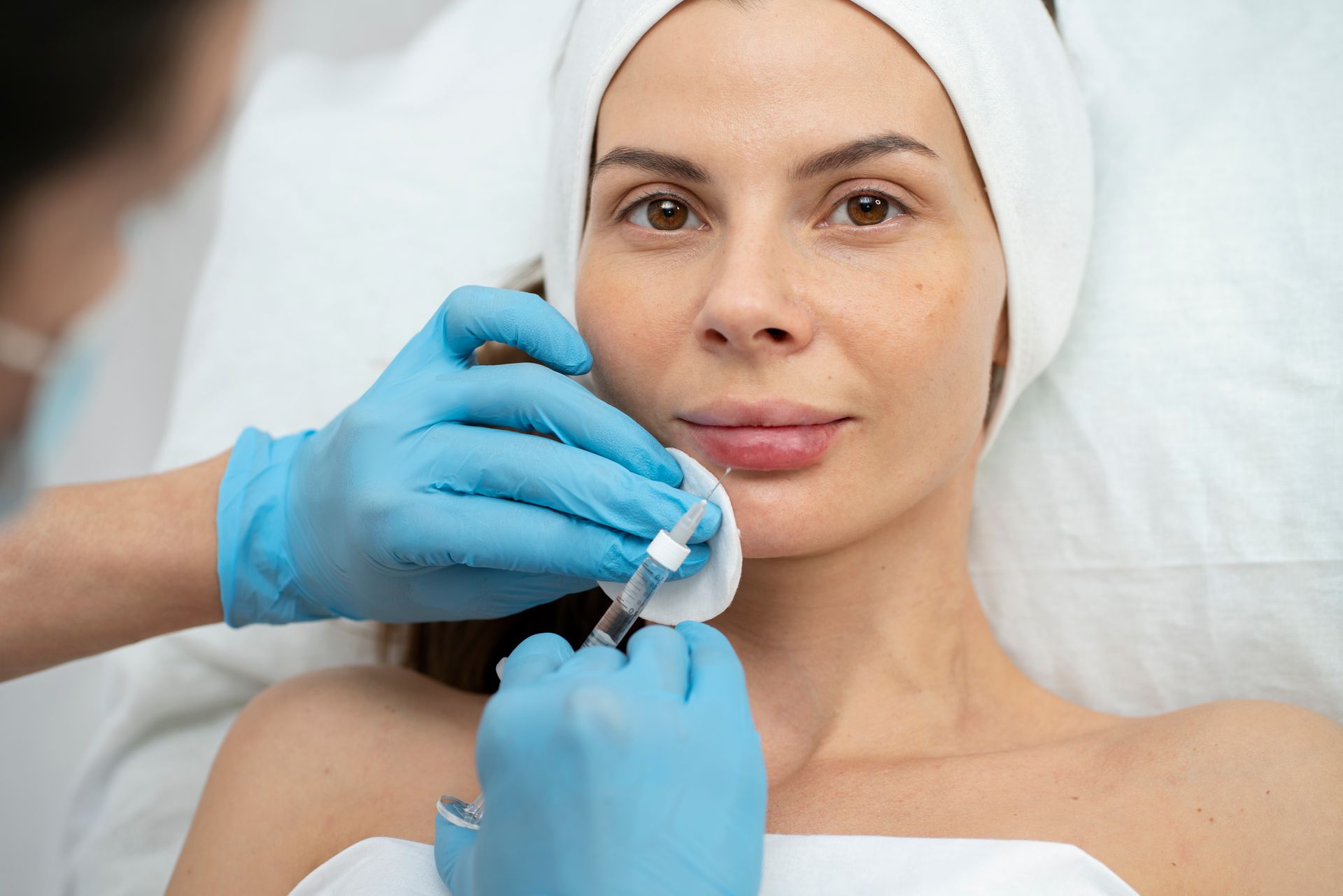 Cosmetic treatment on woman’s face with gloved hands applying a small device during a facial procedure