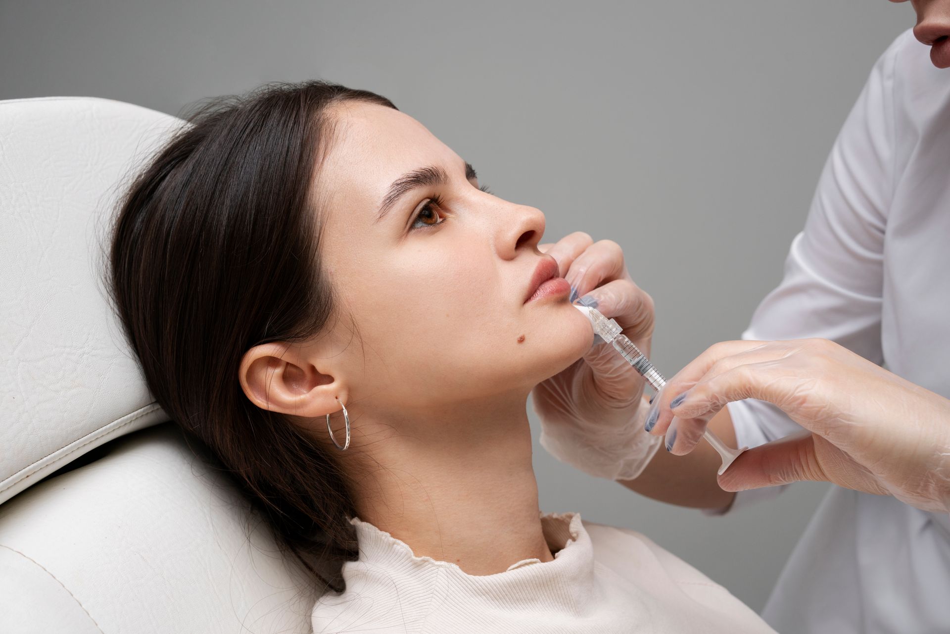 Woman gently touching her neck with eyes closed against a white background