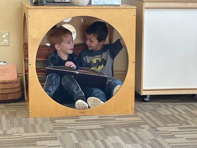 Two boys are sitting in a circle reading a book