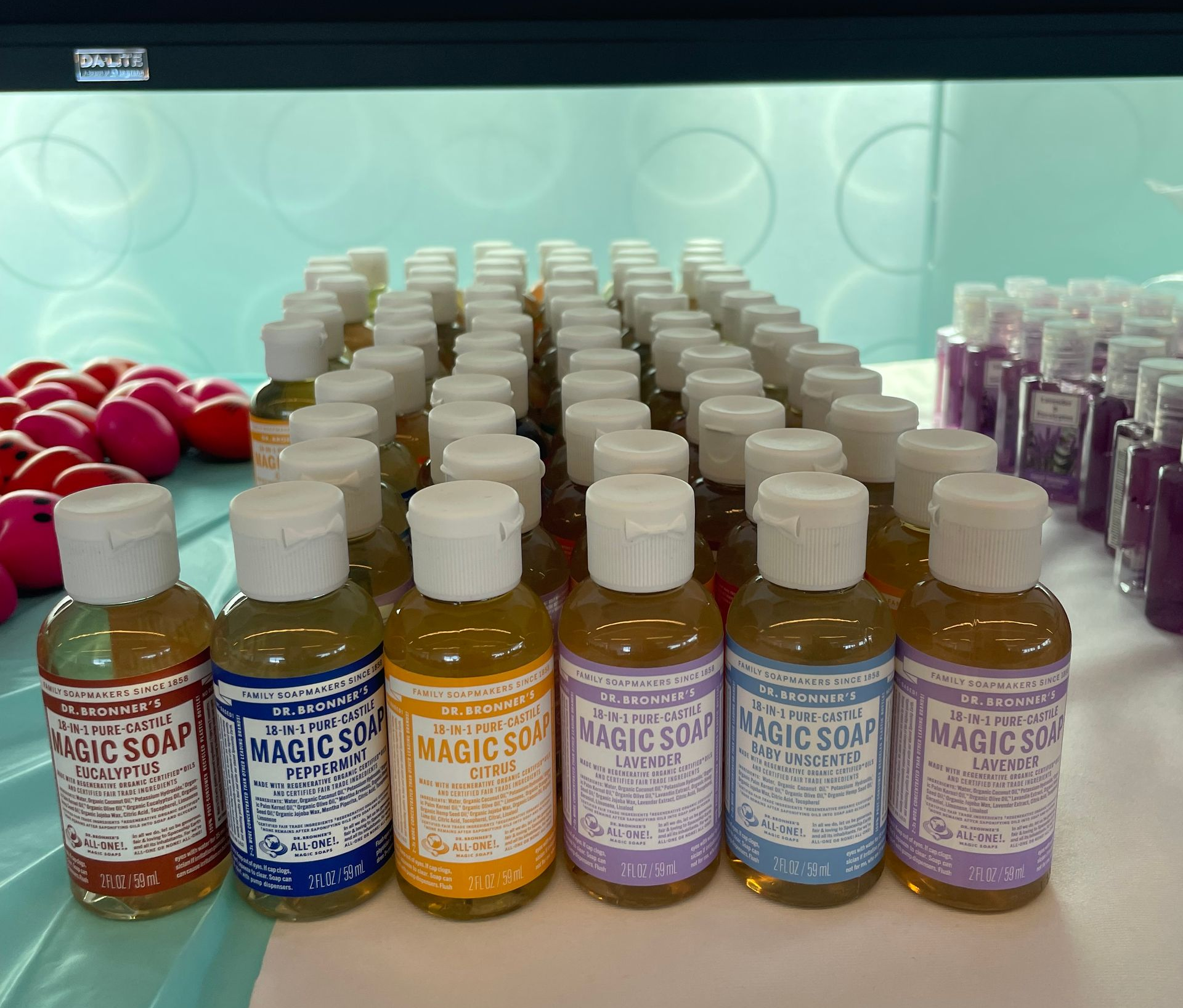 Rows of small bottle Dr. Bronner's with colorful labels displayed on a table in a pharmacy-like setting