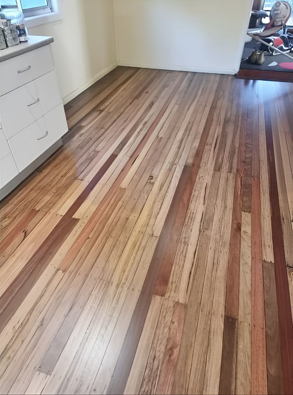 A Kitchen With A Wooden Floor And White Cabinets — Kyall Chalker Floor Sanding & Polishing In Macquarie, NSW