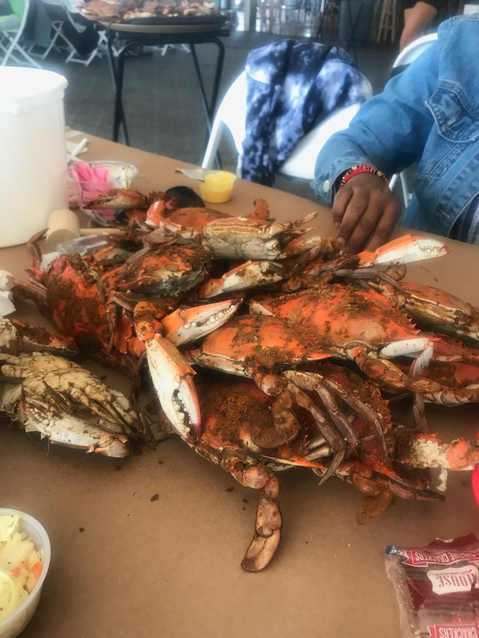 Platter of grilled crabs on a table, with a person’s hand reaching in to eat.