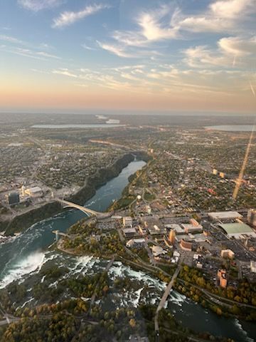 Aerial view of a city at sunset with a river, bridges, and a sprawling urban landscape.