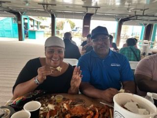 Two people smiling at a restaurant table, eating seafood with bowls and plates in front of them.