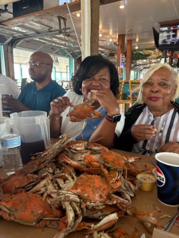 Three people at a table with a large pile of crabs and seafood in a casual restaurant.