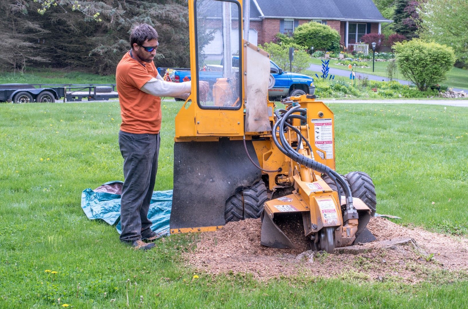 A man is using a stump grinder to remove a tree stump.